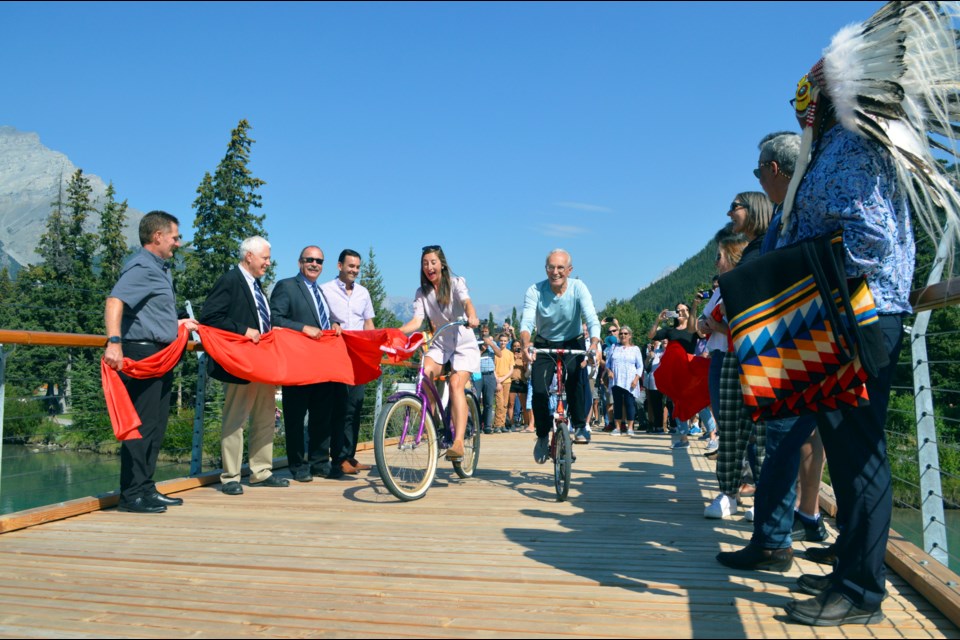 Banff Mayor Corrie DiManno and Wim Pauw, founder of the Wim and Nancy Pauw Foundation, bike across the new Nancy Pauw Bridge during the ribbon cutting of the grand opening on Tuesday (Sept. 6). The new pedestrian bridge connects Central Park and the Banff Recreation Grounds over the Bow River. JORDAN SMALL RMO PHOTO
