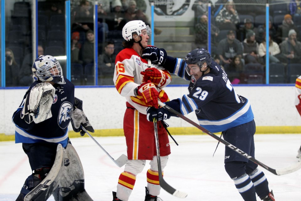 Canmore Eagles defenceman Ryan Nolan, right, tries to clear Calgary Canucks Matt Corbet away from the front of the net during a Canucks power play on Sunday (Jan. 1) in Canmore. JORDAN SMALL RMO PHOTO