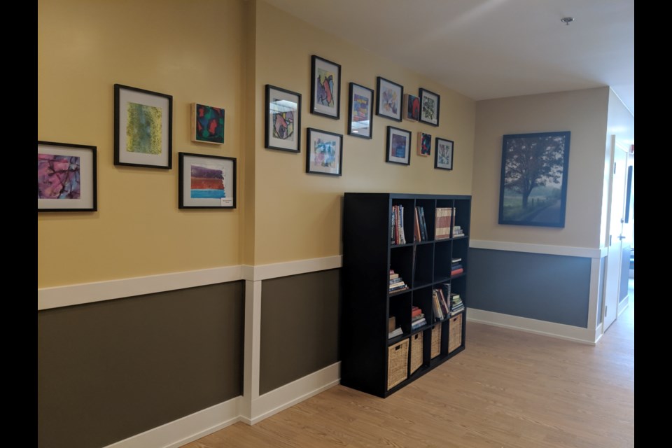 A hallway with artwork and a book shelve mimics the feeling of home. 