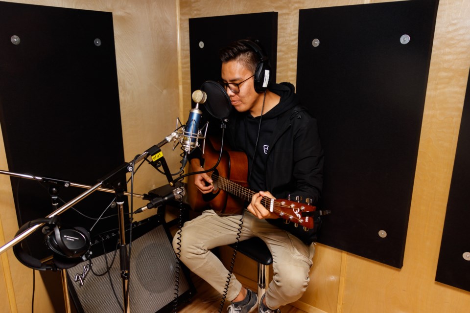 Sandis Twoyoungmen strums a guitar in the sound booth of the Wapikoni studios mobile trailer in Stoney Nakoda on Tuesday, Oct. 15, 2019. The travelling audiovisual creation studio travels across Canada giving Indigenous youth creators the chance to work on media projects. CHELSEA KEMP RMO PHOTO