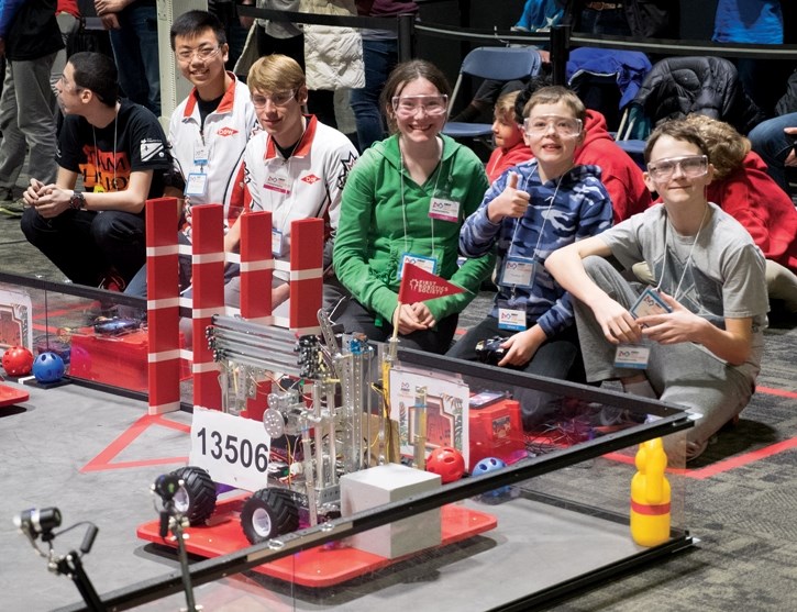 Our Lady of the Snows Catholic Academy team with their robot #13506 before the start of a round. From right to left are Oliver Langhorst (grey), Thomas Paul and Erin Berry.