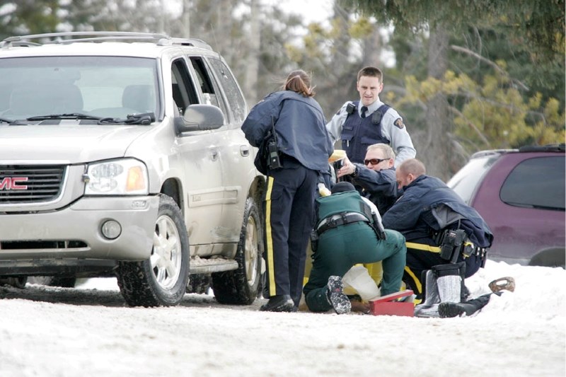 RCMP officers stand over a suspect with a gunshot wound to his lower body that has also been incapacitated with a Taser. The man fled from police in Banff earlier Friday