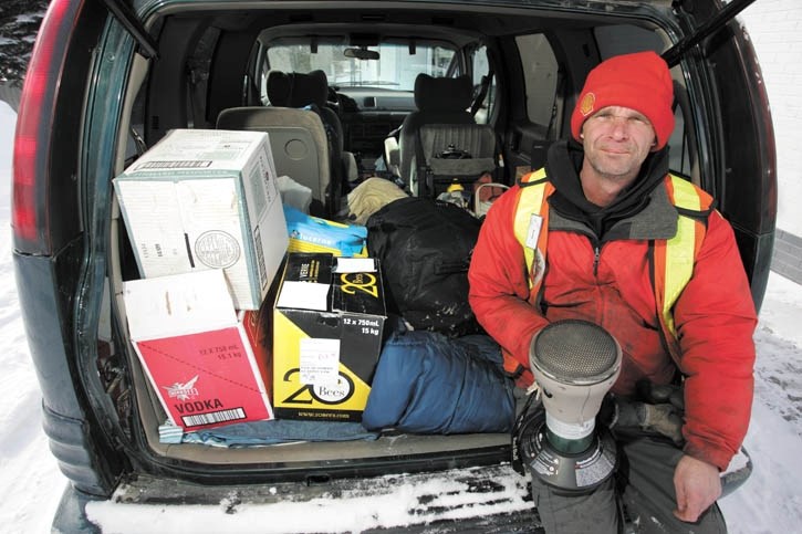 Kevin Myers holds a propane heater as he sits in his van, which doubles as his temporary home.