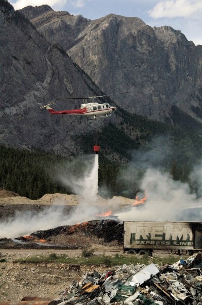 A helicopter dumps water on the burning woodpile Sunday.