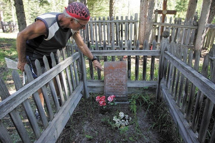 Denis Roy inspects a typical wood-fenced grave site at the Canmore Cemetery.