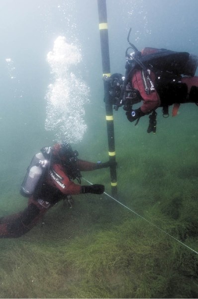 Underwater archeologists prepare a core sampling tube used to extract sediments deep within the lake bed.