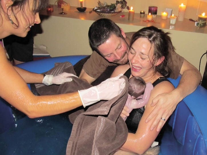 Meghanne Reburn, left, aids a happy couple with a water birth.