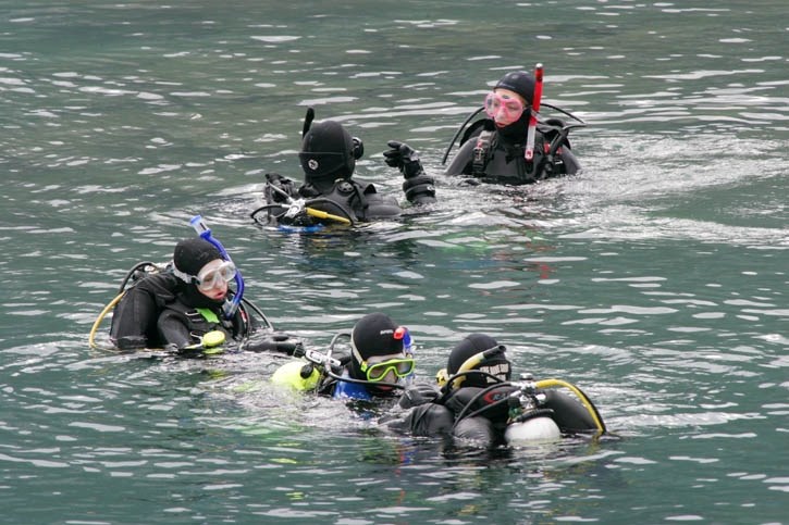 A large group of divers prepare to descend into the depths of Lake Minnewanka. The mountain lake is a popular location for dive school operators in both summer and winter.