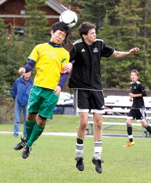 Canmore Crusader captain Jiho Chan beats Holy Trinity Academy Knight Nolan Young to a header during the zone high school soccer final at Millennium Field in Canmore, Monday