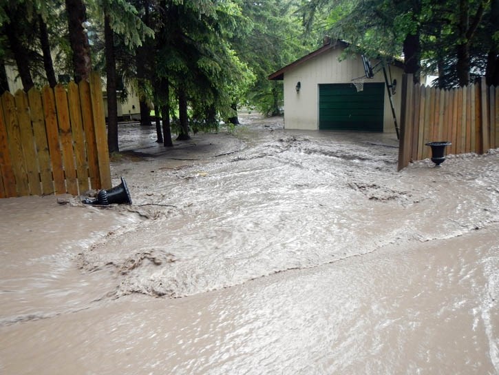A Lac Des Arcs property is inundated by water and mud as floodwater pours through the hamlet.