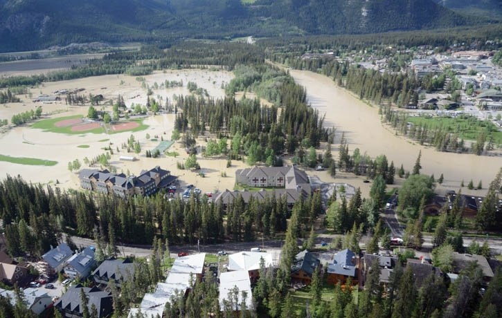 An aerial view of Banff shows the Bow River, Banff Rec Grounds, Warner Stables and Rocky Mountain Housing Co-op all struggling with a massive volume of water.