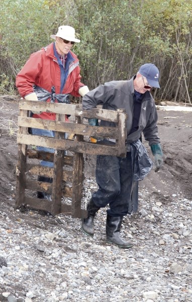 Frank MacIntyre, front, and Doug Cooper haul a waterlogged pallet out of the brush along Pigeon Creek in Three Sisters Campground in Dead Man’s Flats, Sept. 30.
