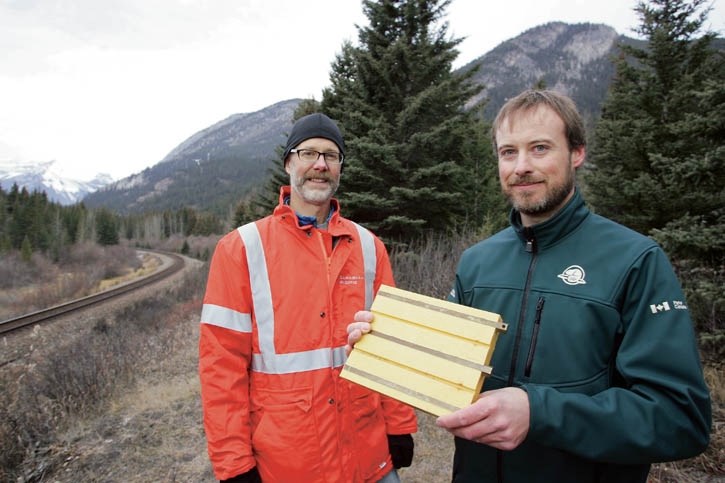 CP Rail’s Chris Bunce looks on as Parks Canada wildlife biologist David Gummer holds a model of an electro mat at a high train/wildlife collision location west of the Banff