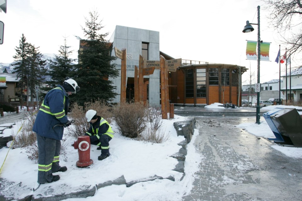 Crews work outside the Civic Centre in Canmore after a pipe in the facility’s women’s washroom burst overnight flooding the building and the surrounding streets.