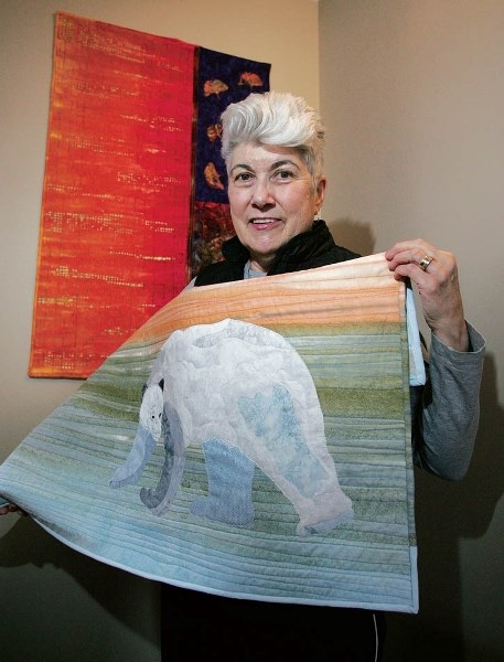 Lynn Cooper shows off a polar bear themed quilt, titled, Getting Warmer, and a second titled, Eastern Influence. Both pieces will be part of the upcoming Mountain Cabin