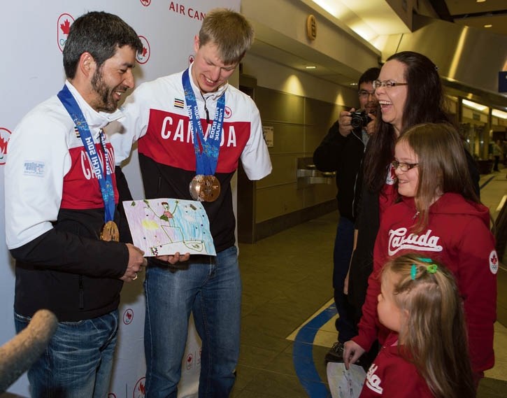 Canadian Paralympic Medallists Brian McKeever, left, and Mark Arendz, centre, receive a special gift from supporters Karri Quan, rear, Marah Rubak, 10, and Camelia Rubak, 4,