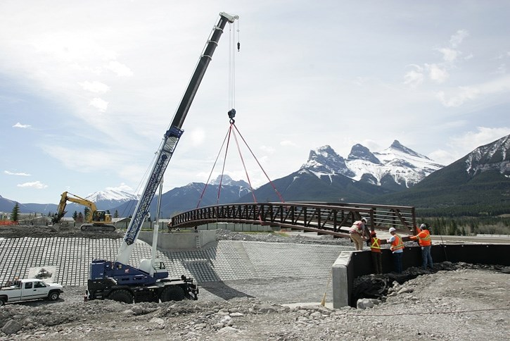 A pedestrian bridge is lifted into place across Cougar Creek, north of the Trans-Canada Highway, Wednesday (May 21). The bridge was originally located further upstream on the 