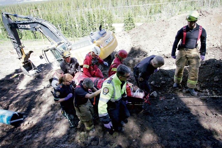Emergency service personnel remove an injured worker after he was buried entirely for more than three minutes near Dead Man’s Flats Saturday (June 21). The man suffered