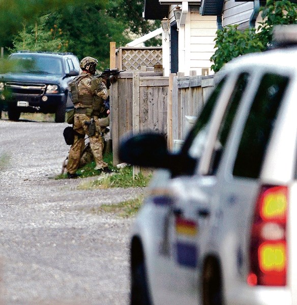 RCMP tactical members stand guard at the rear of 92 Quigley Drive in Cochrane as a standoff between police and a suspected gunman took hours to end on Aug, 17.