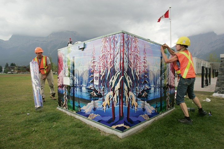 Shaun and Joanne Peirson install locally-sourced artwork on a transformer box at Centennial Park in Canmore. The works can be found throughout Canmore.