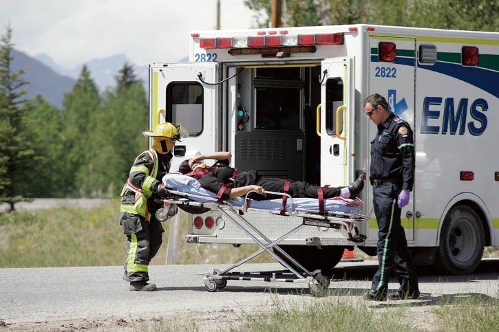 A Canmore Fire-Rescue member helps EMS paramedics load a patient into an ambulance last week.