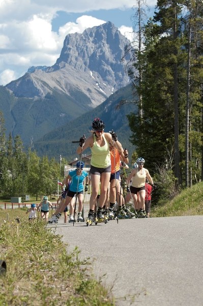 Female athletes rollerski at the Canmore Nordic Centre.
