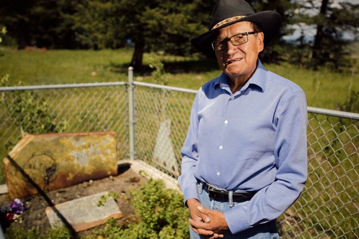 Renowned artist and Stoney elder Roland Rollinmud stands at Chief John Chiniki’s gravesite at the Chiniki Cemetery near Morley. Near the grave the ‘Telling Our Stories’ sign