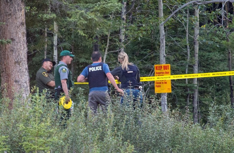 RCMP, Conservation and Fish and Wildlife officers tape off a trail bordering Three Sisters Parkway where a bear attack occurred in Canmore on Wednesday (July 20).