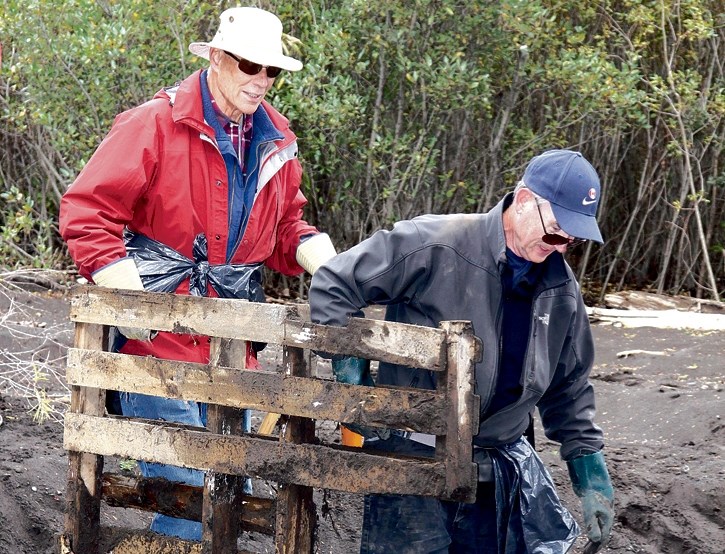 Frank MacIntyre, front, and Doug Cooper haul a waterlogged pallet out of the brush along Pigeon Creek in Three Sisters Campground in Dead Man’s Flats in 2013.
