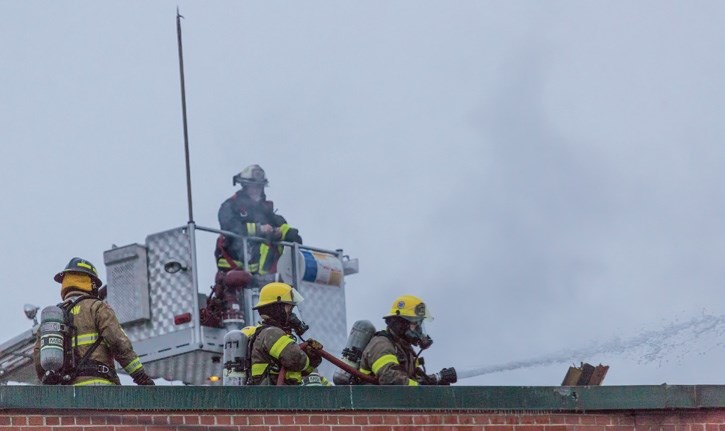 Crews from Exshaw and Lake Louise fire departments tackle flairups on the rear of the hotel.