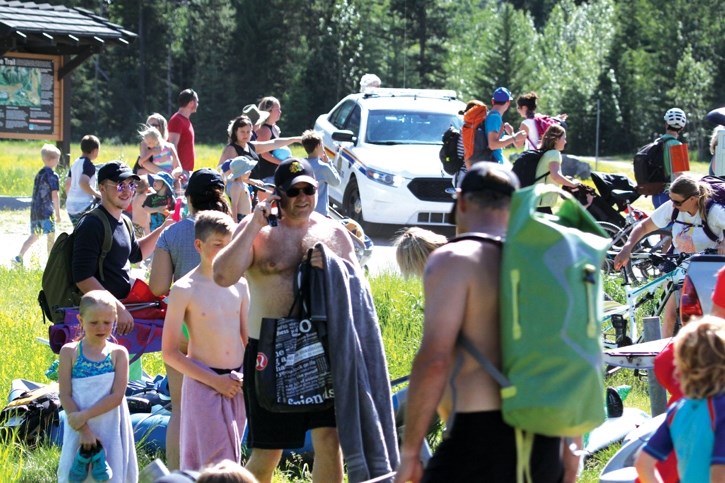 A crowd of people leave the Quarry Lake area Monday (July 3) after the site was closed due to bear 148s proximity. RCMP, Fire-Rescue, Fish and Wildlife and Town bylaw staff