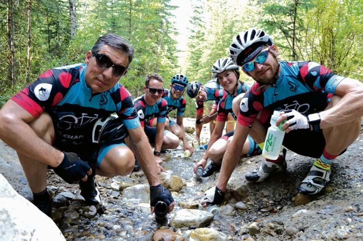 Filling up at Canmores spring water stream are Wheels for Wells cyclists John Audia, left, Kory Howard, Mac Potter, Paulo Stroud-Baranda, Jaylene Kemp and David Custer (not
