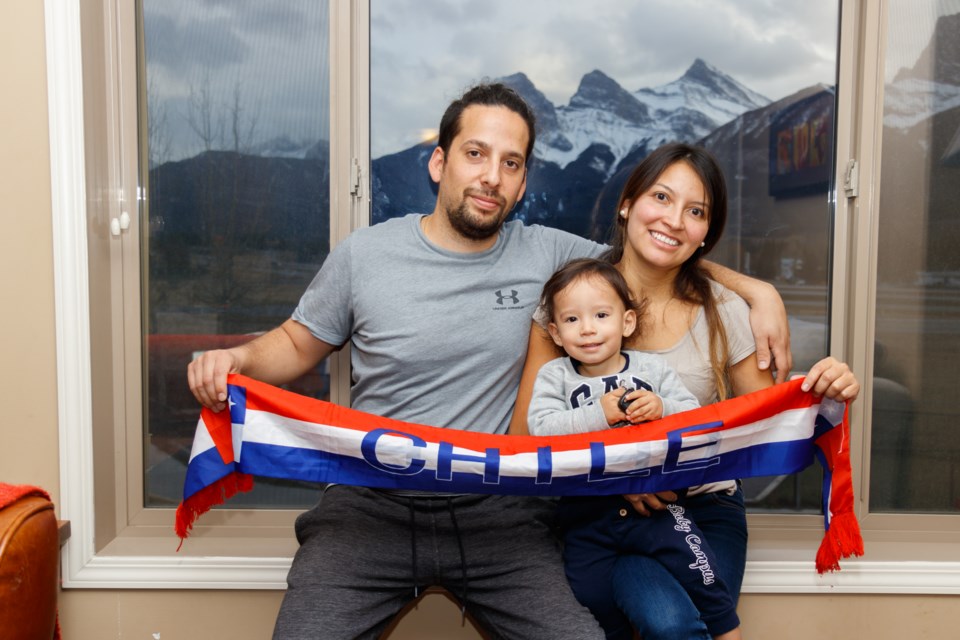 Marcelo Andres Fernandez Reyes, left, his wife Fernanda Lopez Salazar and their 18-month-old son Javier Fernandez Lopez hold a banner supporting Chile in their home on Tuesday (Oct. 22). CHELSEA RMO PHOTO