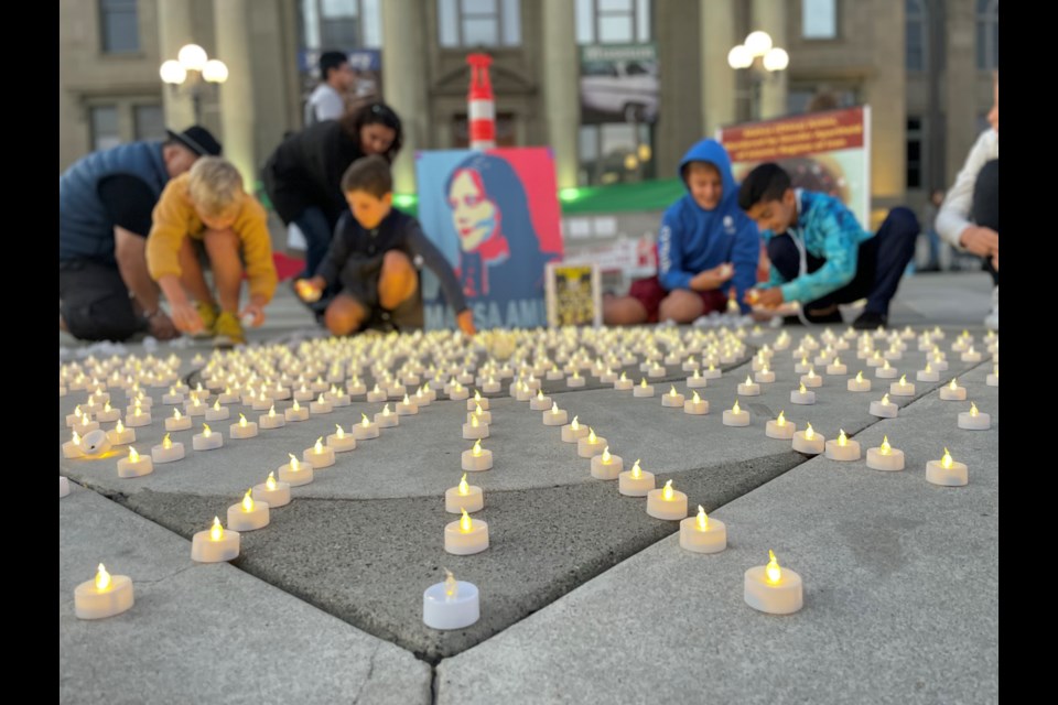 Children place candles at the altar for 22-year-old Mahsa Amini