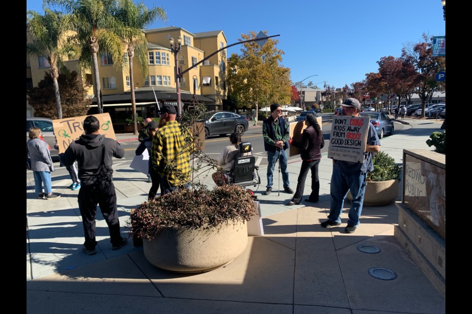 Protestors stand outside the library holding signs