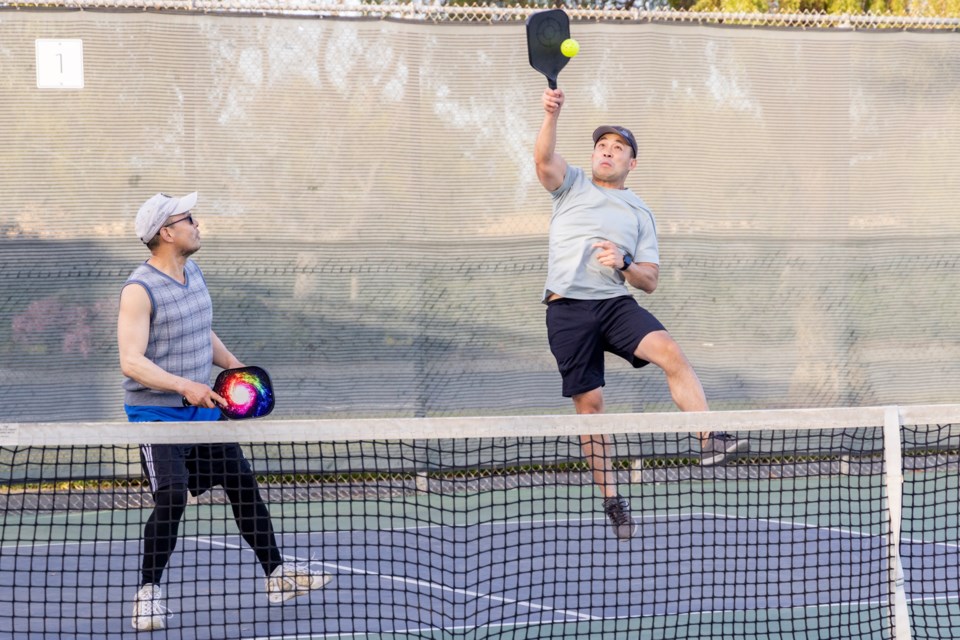 Denny Hsu (right) hits a pickleball during play with Winston Chen in Foster City. Photo by Devin Roberts.