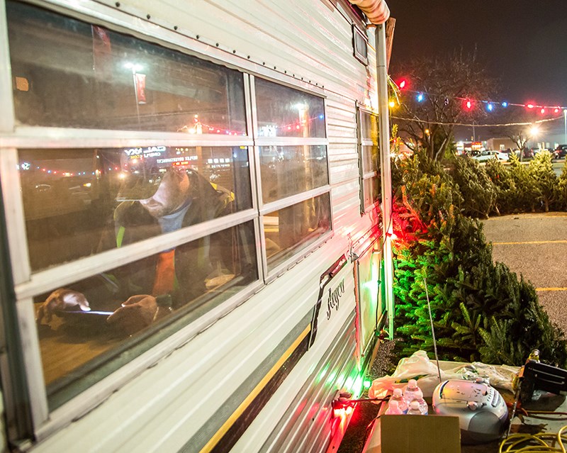 Chris Churchill warms up in a trailer between customers on his family's Christmas tree lot. Troy Shantz