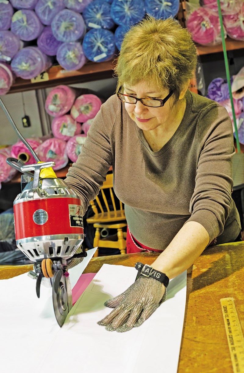 Karen Folk cuts patterns for 20 layers of material used to make girls costume dresses at the Point Edward manufacturing Centre. Glenn Ogilvie