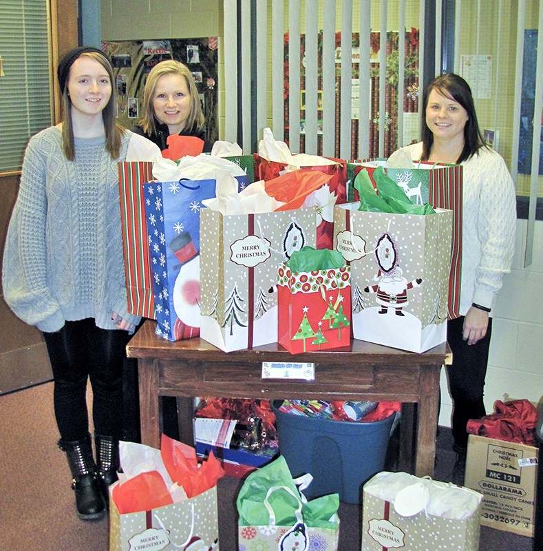 Tammy Froude, centre, with daughter Taylor, 16, left, turns over 10 of the secret Santa gifts for distribution to Salvation Army administrative assistant Ashley Bird, right. Submitted Photo
