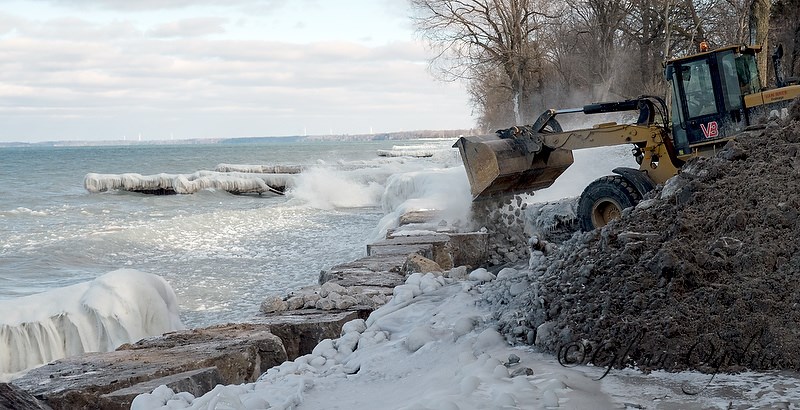 A backhoe from Van Bree Drainage and Bulldozing backfills a repaired section of the Lake Huron Shoreline just east of the Cull Drain Bridge.  