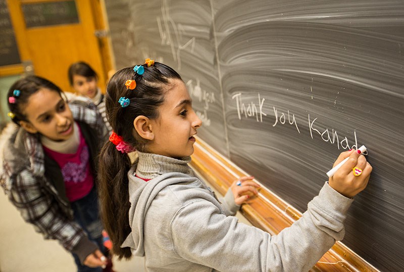 Raghad Al-Khaleel, 8, expresses her family's feelings on a blackboard at the YMCA Learning and Career Centre, while sisters Rooa, and Rahaf look on. Troy Shantz, Special to The Journal