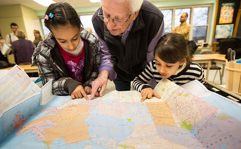 Pastor Harry Mennega looks over a map of Canada with Rooa, 10, left, and Rahaf Al-Khaleel, 6. Troy Shantz, Special to The Journal