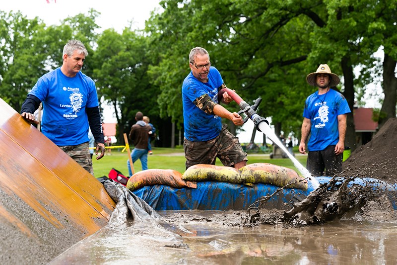 Volunteer Marty Vanos sprays one of the mud pits while Dave Schoch looks on during the 2015 Assante Dirty Dash for Rebound. Photo courtesy of Edward Allen