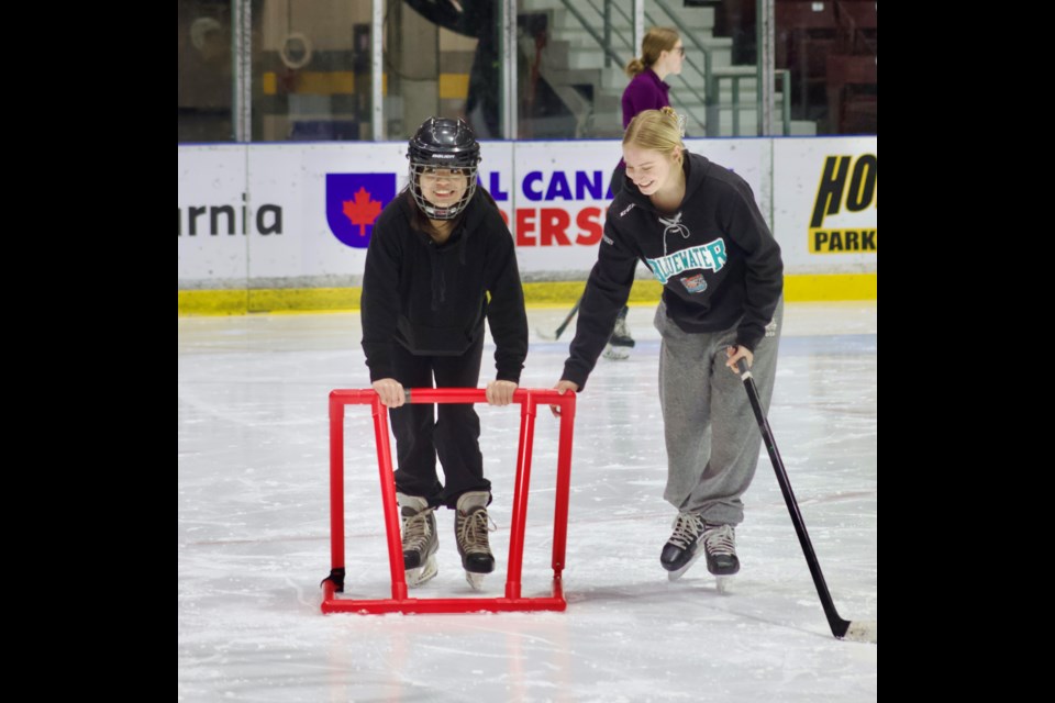 Keely Richardson (right), a Grade 11 student and hockey player at St. Pat’s, lends a hand as Raisel Ibasco learns to skate.
