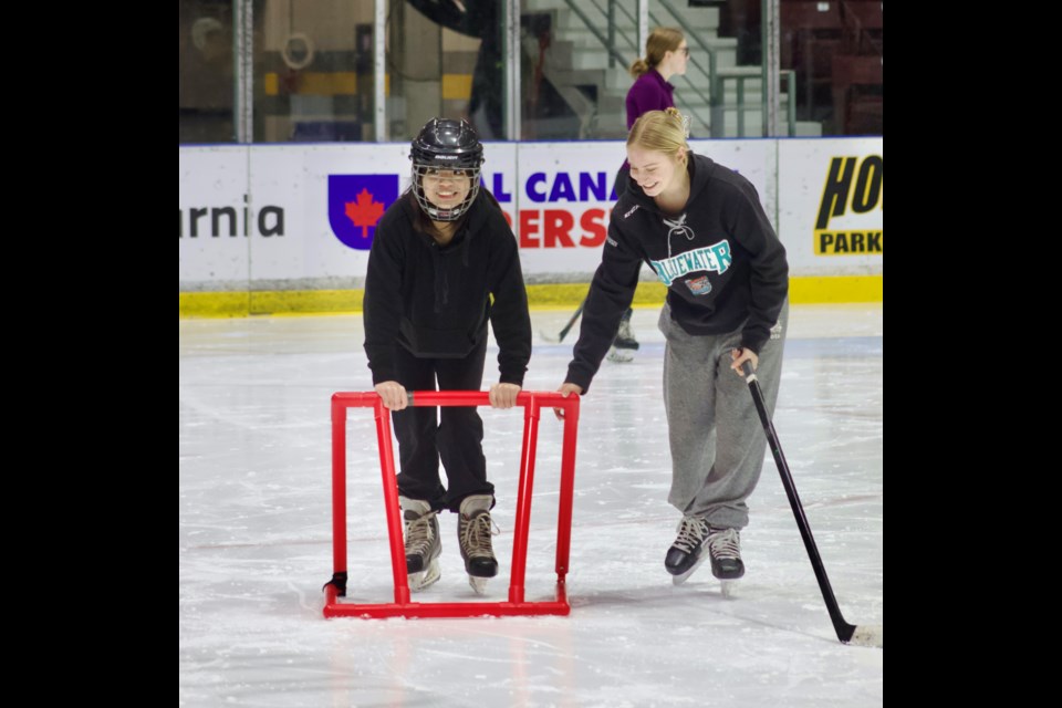 Keely Richardson (right), a Grade 11 student and hockey player at St. Pat’s, lends a hand as Raisel Ibasco learns to skate.
