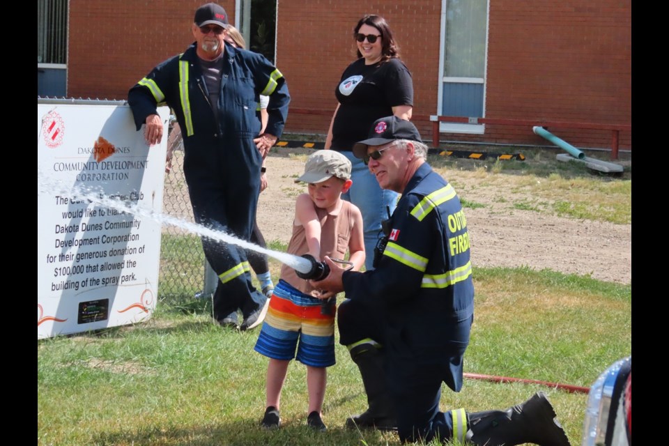 Don Hurd shows a youngster how the fire hose works. Photo by Derek Ruttle.