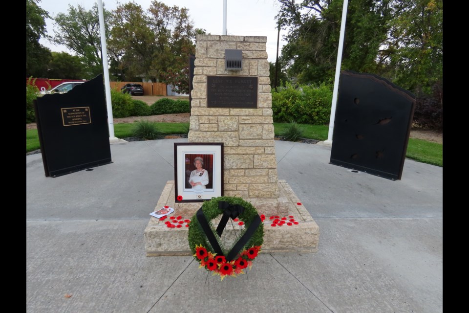 A portrait of Queen Elizabeth is surrounded by a wreath and poppies at the conclusion of the morning event.