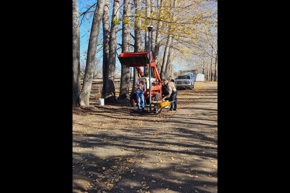 Deryl Richards and Bob Schwab work to install new lights along the paths between the ball diamonds.