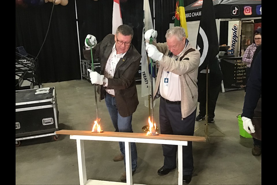 Premier Scott Moe and longtime ag reporter Jim Smalley take part in the burning of the brands to launch Agribition.