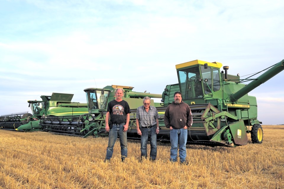 Brian Wenzel, left, was helping Robert and Todd Adams harvest in late September and into early October using his father's 1975 combine (right)                               